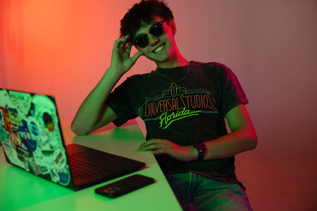 Chase McLean at a desk with a laptop, lit in red and green